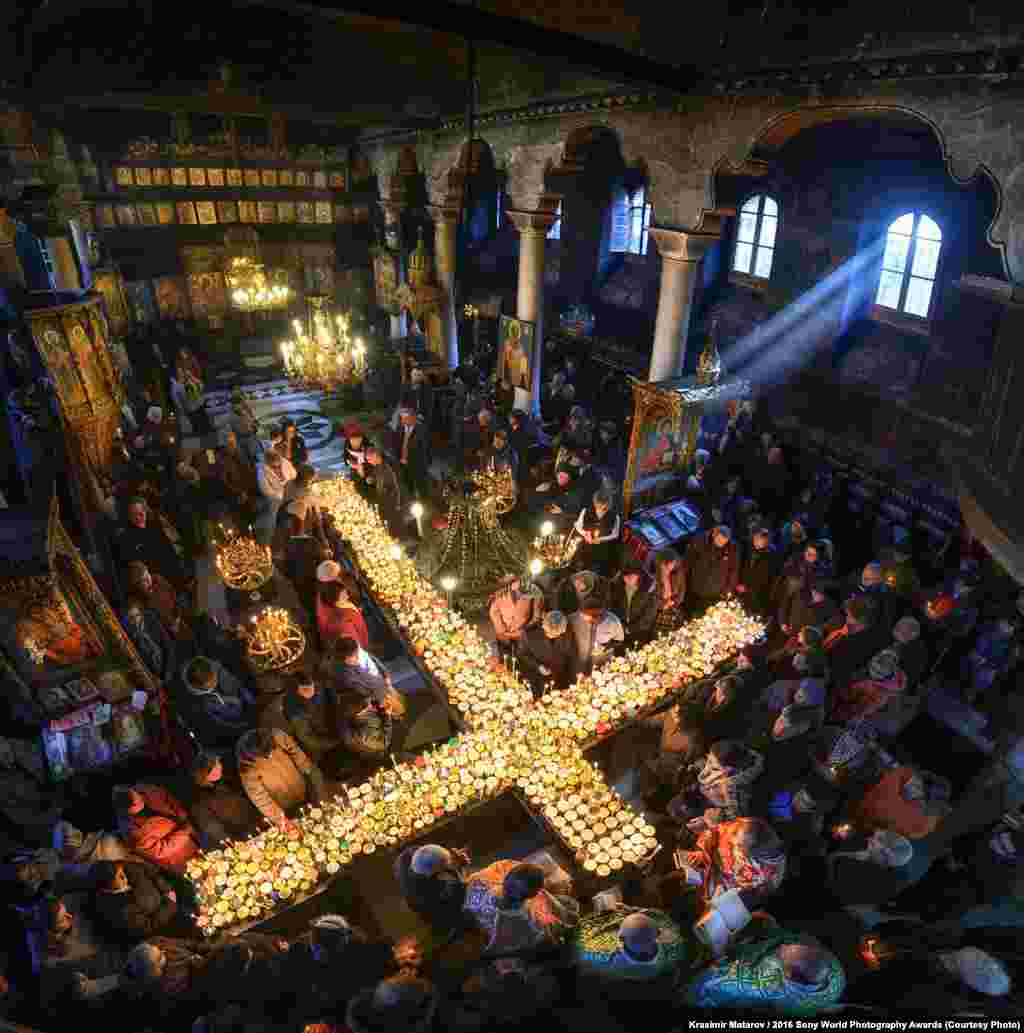 Photographer Krasimir Matarov of Bulgaria: St. Haralambos Jars of honey are blessed to celebrate the feast day of St. Haralambos, the day of the beekeepers. On that day, people bring jars to the church to be blessed. There is a tradition to light candles attached to the honey jars and put them on tables ordered in the shape of the cross.