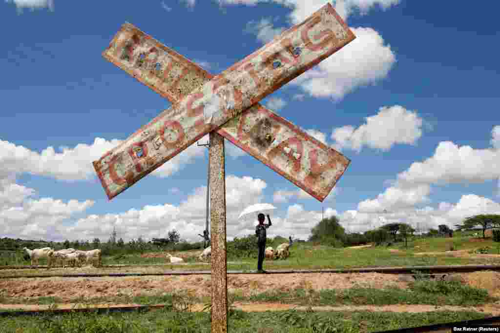 A child holds an umbrella as he stands on SGR railway tracks near the town of Kiu, south of Nairobi, Kenya, December 16, 2019.