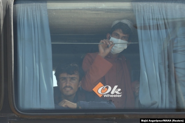 Afghans look out a a bus at the Dowqarun border crossing between Iran and Afghanistan in late August 2021.