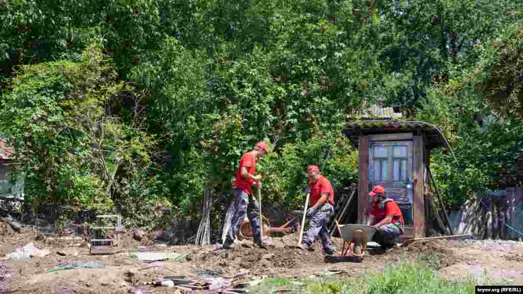 Приезжие волонтеры из российской республики Тыва помогают местной пенсионерке очистить приусадебный участок от остатков селевой лавины