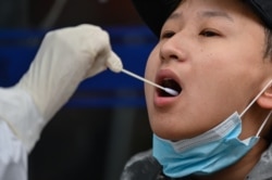 Медичний працівник бере зразок у людини, яка буде проходити тест на COVID-19 в Ухані, Китай, 30 березня 2020 року