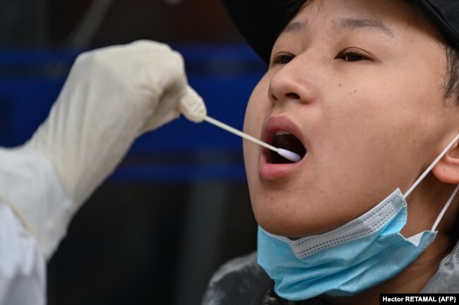 A medical worker takes a swab sample from a person to be tested for COVID-19 in Wuhan, China, on March 30.