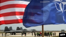 The U.S. and NATO flags fly in front of two U.S. Air Force F-22 Raptor fighter jets at the air base in Siauliai, Lithuania, on April 27.