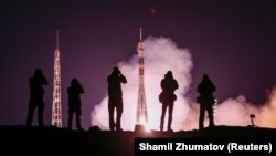 Photographers take pictures as the Soyuz MS-12 spacecraft carrying the three-person crew blasts off on March 14. 