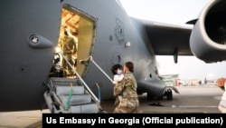 آرشیف، یک سرباز امریکایی همراه با یک کودک افغان در حال سوار شدن به یک طیاره نظامی این کشور