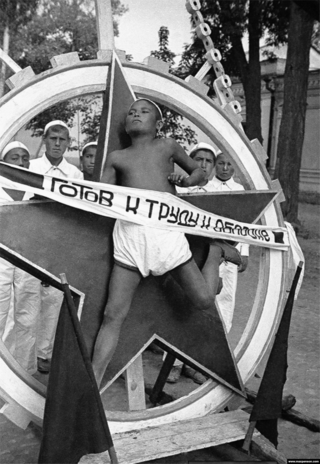 A boy serving as a &quot;Live Emblem&quot; during a march in central Tashkent. The banner proclaims a readiness &quot;for labor and defense!&quot;