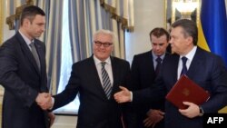 German Foreign Minister Frank-Walter Steinmeier (center) and opposition leader Vitali Klitschko (left) shake hands as Ukrainian President Viktor Yanukovych (right) gestures after signing an agreement in Kyiv on February 21.