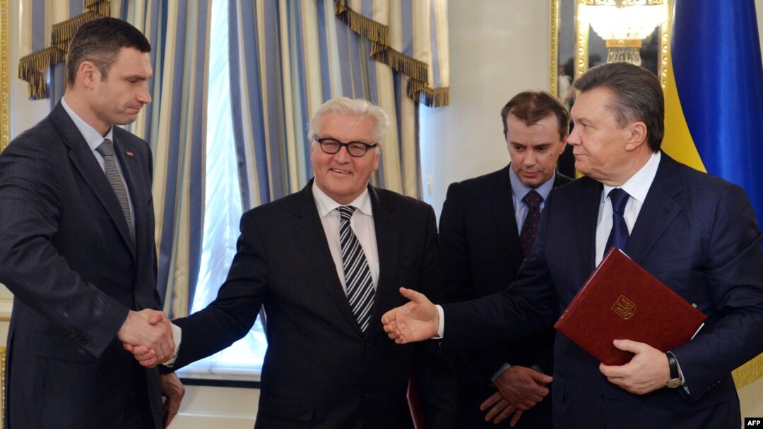 German Foreign Minister Frank-Walter Steinmeier (center) and opposition leader Vitali Klitschko (left) shake hands as Ukrainian President Viktor Yanukovych (right) gestures after signing an agreement in Kyiv on February 21.