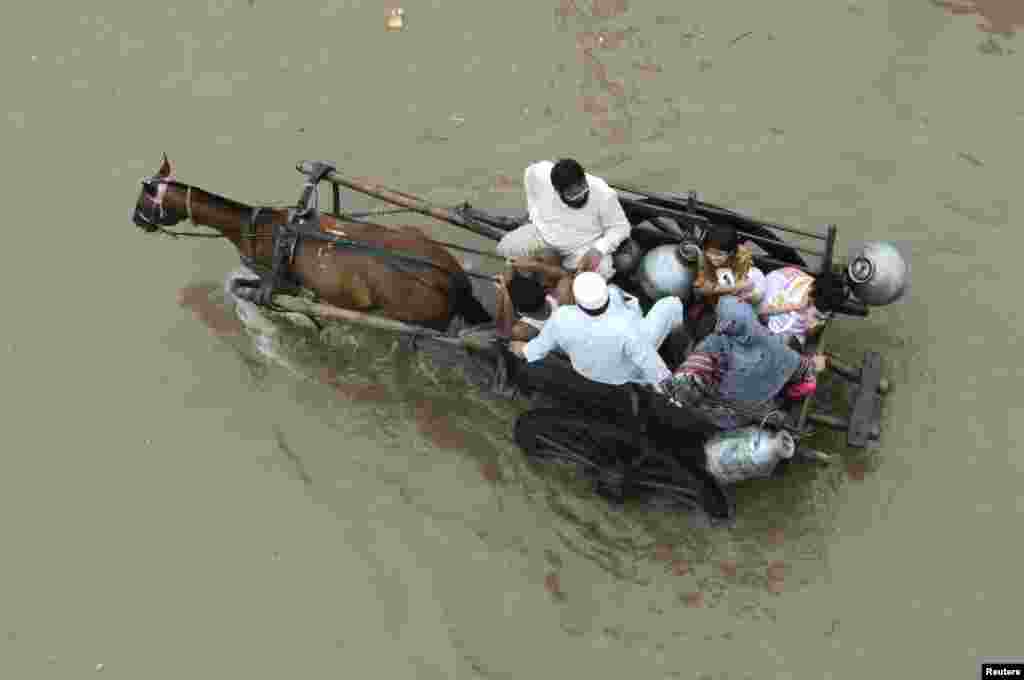 A Pakistani family travels on a horse cart on a flooded road in Lahore.