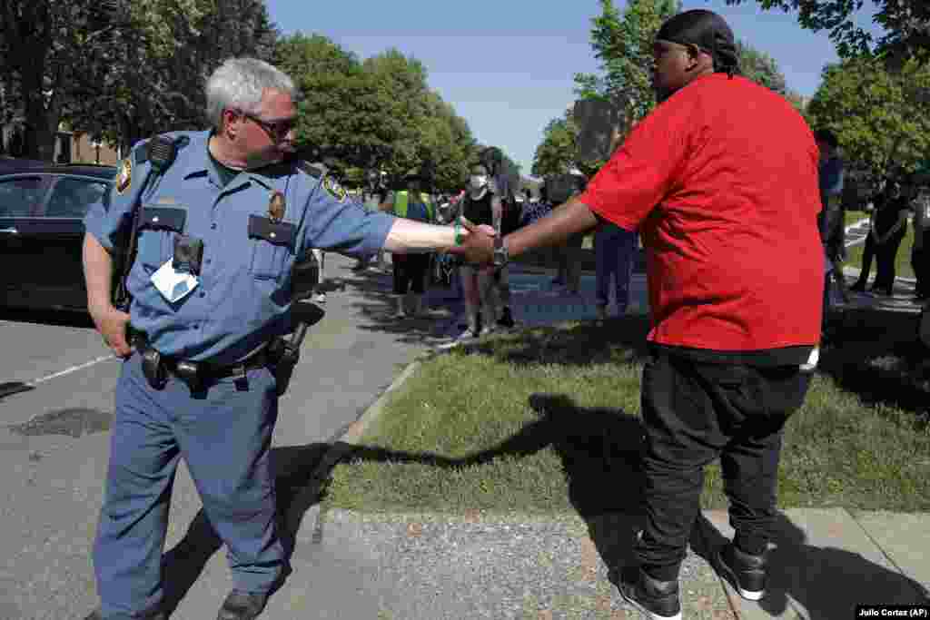 Protests St. Paul -- Gemini Stone Pollard, right, shakes hands with a police officer Monday, June 1, 2020, in St. Paul, Minn. Protests continued following the death of George Floyd, who died after being restrained by Minneapolis police officers on Memorial Day.