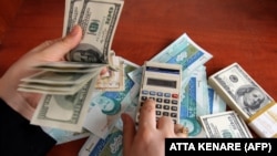 A dealer counts the US dollar banknotes as Iranian Rial currency are seen in a currency exchange office in a shopping center in Tehran on December 22, 2010.