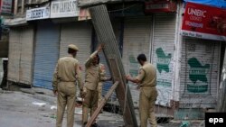 Indian police officers erect a tin and barbed wire barricade in Srinagar, the summer capital of Kashmir on July 11.
