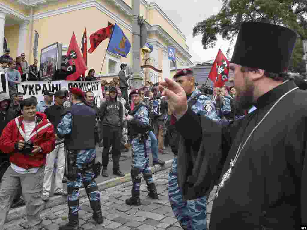 Ukraine -- An Orthodox priest blesses demonstrators who protest against Russian Orthodox Patriarch Kirill, Kyiv, 27Jul2009 - Caption: epa01808072 An Orthodox priest of Moscow patriarchate blesses protestors, who protest against Russian Orthodox Church Patriarch Kirill visiting and demand the independence for Ukrainian church in Kiev, Ukraine, 27 July 2009. Patriarch Kirill arrived to Ukraine at Monday with his Archpastoral Visit.
