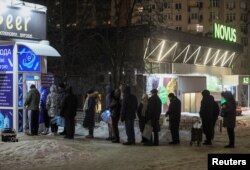 Locuitorii stau la coadă pentru a umple sticle cu apă potabilă, în timpul întreruperilor de curent din Kiev. 24 ianuarie 2026.