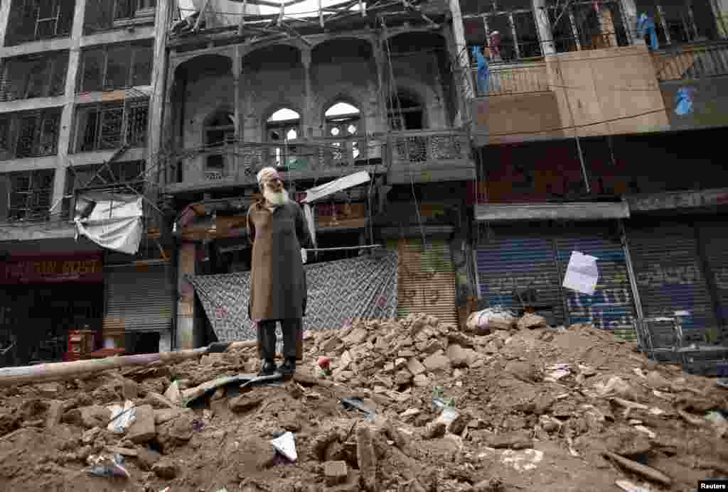 A man stands on a pile of rubble in front of a damaged building after it was hit by a bomb blast in Peshawar, Pakistan. (Reuters/Fayaz Aziz)