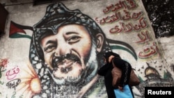 A woman walks past a mural depicting the late Palestinian leader Yasser Arafat in Gaza City.