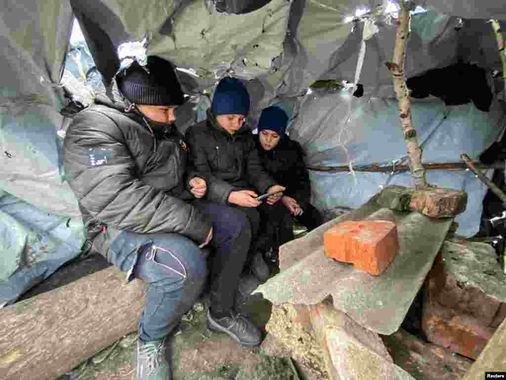 Three boys attend an online class in a makeshift classroom they built using wooden poles and plastic sheeting on the only hill that catches mobile Internet in the village of Hontarivka, Kharkiv region, Ukraine.&nbsp;