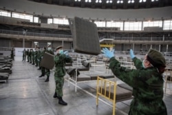 სერბეთის ჯარისკაცები კორონავირუსის მსუბუქი სიმპტომების მქონე პაციენტების განსათავსებლად საწოლებს ამზადებენ ბელგრადის ბაზრობისთვის განკუთვნილ დარბაზში. 24 მარტი.