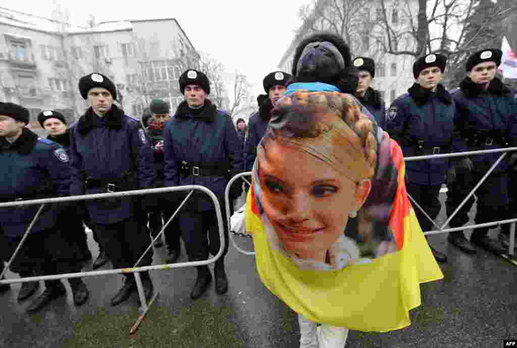 An activist wears a banner with a portrait of Yulia Tymoshenko as she attends a protest rally in front of President Viktor Yanukovych's offices in Kyiv. (AFP/Sergei Supinsky)