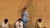 Villagers , their clothes stained with the blood of victims, rest after helping with rescue efforts following a suicide bombing near a mosque in the semi-tribal village of Darra, Pakistan