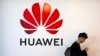 Një burrë duke kaluar pranë një tabele me logon e gjigantit kinez të teknologjisë Huawei, në Pekin.