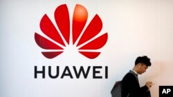 Një burrë duke kaluar pranë një tabele me logon e gjigantit kinez të teknologjisë Huawei, në Pekin.