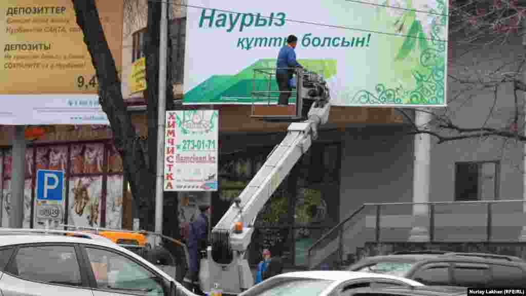 На пересечении улиц Панфилова и Кабанбая рабочие устанавливают билборд с поздравлением с Наурызом.