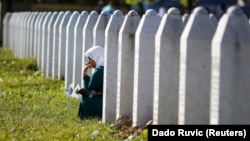 Женщина скорбит среди могил в Мемориальном центре около Сребеницы, где было убито примерно восемь тысяч человек во время Боснийской войны. В то время Сребреница была объявлена ООН «безопасной зоной».