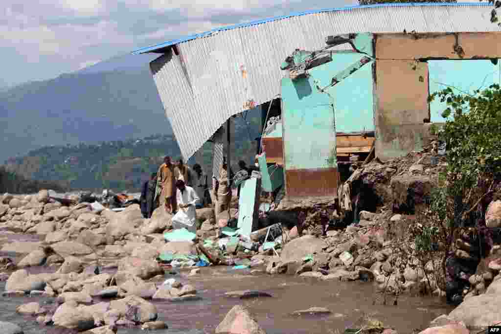 Pakistani Kashmiris look on beside a damaged house, eroded by floodwaters following heavy monsoon rain at Bagh, some 100 kilometers west of Muzaffarabad, the capital of Pakistan-administrated Kashmir.