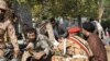 This picture taken on September 22, 2018 in the southwestern Iranian city of Ahvaz shows soldiers and a Shiite Muslim cleric (R) sitting close to the ground seeking cover at the scene of an attack on a military parade.