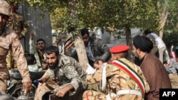 This picture taken on September 22, 2018 in the southwestern Iranian city of Ahvaz shows soldiers and a Shiite Muslim cleric (R) sitting close to the ground seeking cover at the scene of an attack on a military parade.