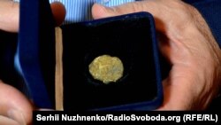 Директор Центру археології Києва Інституту археології України Михайло Сагайдак демонструє реліквію періоду України-Русі – печатку князя Святослава Хороброго (правління: 964–972) із зображення двозуба (праобразу державного герба України – тризуба). Київ, 11 травня 2016 року