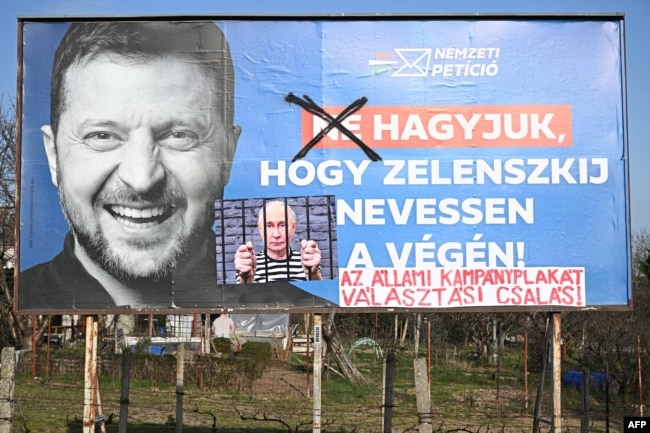 «Виправлений» урядовий білборд із зображенням президента України Володимира Зеленського та гаслом «Не даймо Зеленському сміятися останнім», у Печі, Угорщина, 13 березня 2026 року