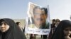 Protesters hold a poster depicting a montage of two faces, Sunni legislator Dhafer al-Ani and Saddam Hussein, and reads below: "Two faces of the same coin."