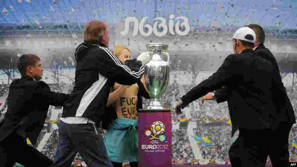 An activist from Ukraine&#39;s radical women&#39;s group FEMEN tries to grab the trophy for the Euro 2012 soccer championship, which was on display in the western city of Lviv on May 24. (AFP/Yuriy Dyachshyn)