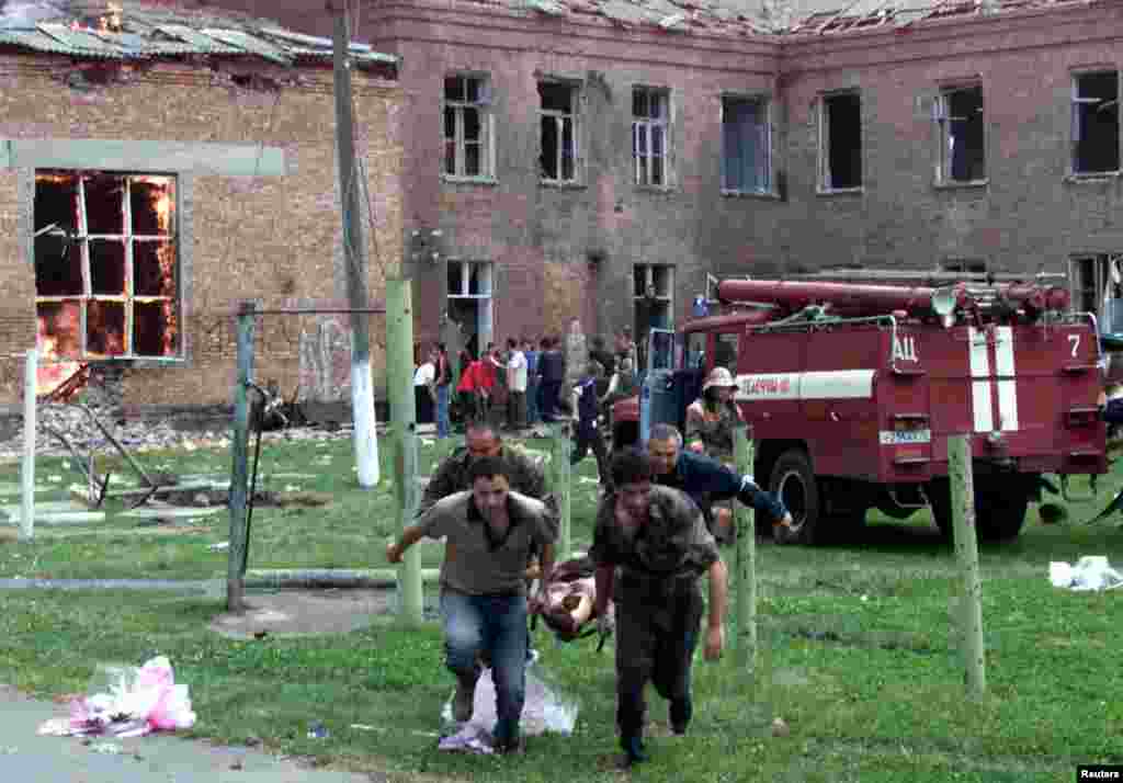 Volunteers carry an injured civilian to safety while soldiers storm the school on September 3, the third day of the hostage crisis. A number of witnesses said they saw tanks fire on the school. Russian authorities&#39; handing of the crisis would come under heavy scrutiny in the wake of the tragedy.