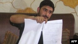 Mukhtar Kazam, the husband of Samia Shahid, displays her postmortem report during a press conference in Rawalpindi, Pakistan, on July 28.