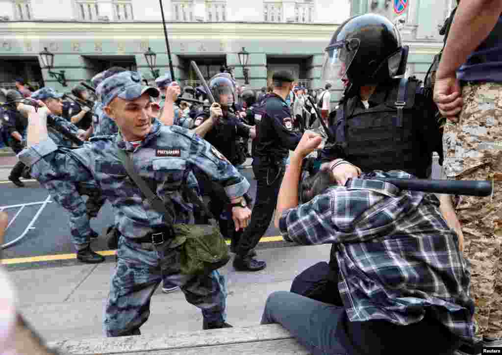 A Russian national guardsman beats a protester with a rubber baton during protests in Moscow. Video of the incident show the guardsman striking the detained man twice with full force, before a bystander punches the riot policeman on right.&nbsp;