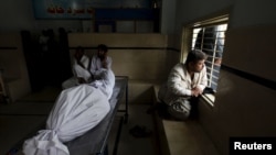 Relatives sit beside a body of a deceased who died due to an intense heat wave in Karachi, Pakistan on June 22.