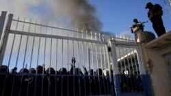 Forcat e Qeverisë siriane bëjnë roje, teksa para portës së kampit Al-Hol janë mbledhur disa gra. Fotografia është shkrepur më 21 janar 2026, pasi forcat kurde u tërhoqën nga kampi.