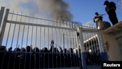 Pripadnici snaga sirijske vlade drže stražu, dok se ispred kapije kampa Al-Hol okupilo više žena. Fotografija je snimljena 21. januara 2026. godine, nakon što su se kurdske snage povukle iz kampa.