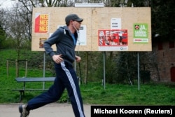 Чоловік пробігає повз білборд із агітаційними плакатами «за» та «проти» угоди про асоціацію між Україною та ЄС напередодні консультативного референдуму з цього питання 6 квітня 2016 року в парку в Утрехті (Нідерланди).