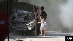 Një nënë palestineze dhe vajza e saj nxitojnë të strehohen gjatë një sulmi izraelit në kampin Al-Bureij në Rripin qendror të Gazës, më 4 korrik 2025.