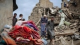 Afghan men walk on the rubble of a damaged house following a deadly magnitude-6 earthquake that struck eastern Afghanistan.