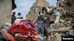 Afghan men walk on the rubble of a damaged house following a deadly magnitude-6 earthquake that struck eastern Afghanistan.