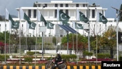 A man rides a motorcycle past the presidential house in Islamabad ahead of US-Iran talks in the Pakistani capital.
