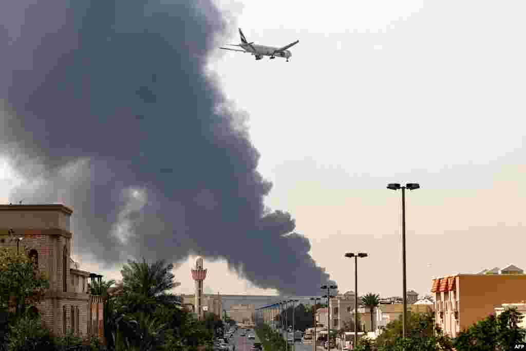 An aircraft prepares to land as plumes of smoke rise near Dubai's International Airport on March 16.Since US-Israeli strikes on Iran began on February 28, Tehran has launched a total of more than 2,000 drones and missiles at the United Arab Emirates, killing at least eight people, authorities in the Gulf state say.