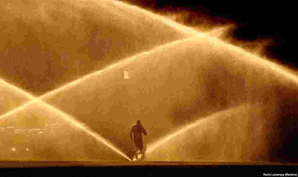 A jogger makes his way past sprinklers alight with the morning sun on a beautiful autumn day in Washington, D.C. (Reuters/Kevin Lamarque)