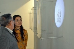 Шекер Шәкір өзінің инсталляциясының жанында тұр.