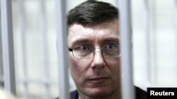 Former Interior Minister Yuriy Lutsenko looks out from the defendant's cage during a court session in Kyiv in February.